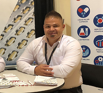 Ben Reed sitting a tall table in a white button-up shirt at a trade show.