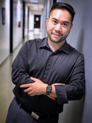 Dr. David Nguyen in a hallway, arms crossed, smiling looking at the camera